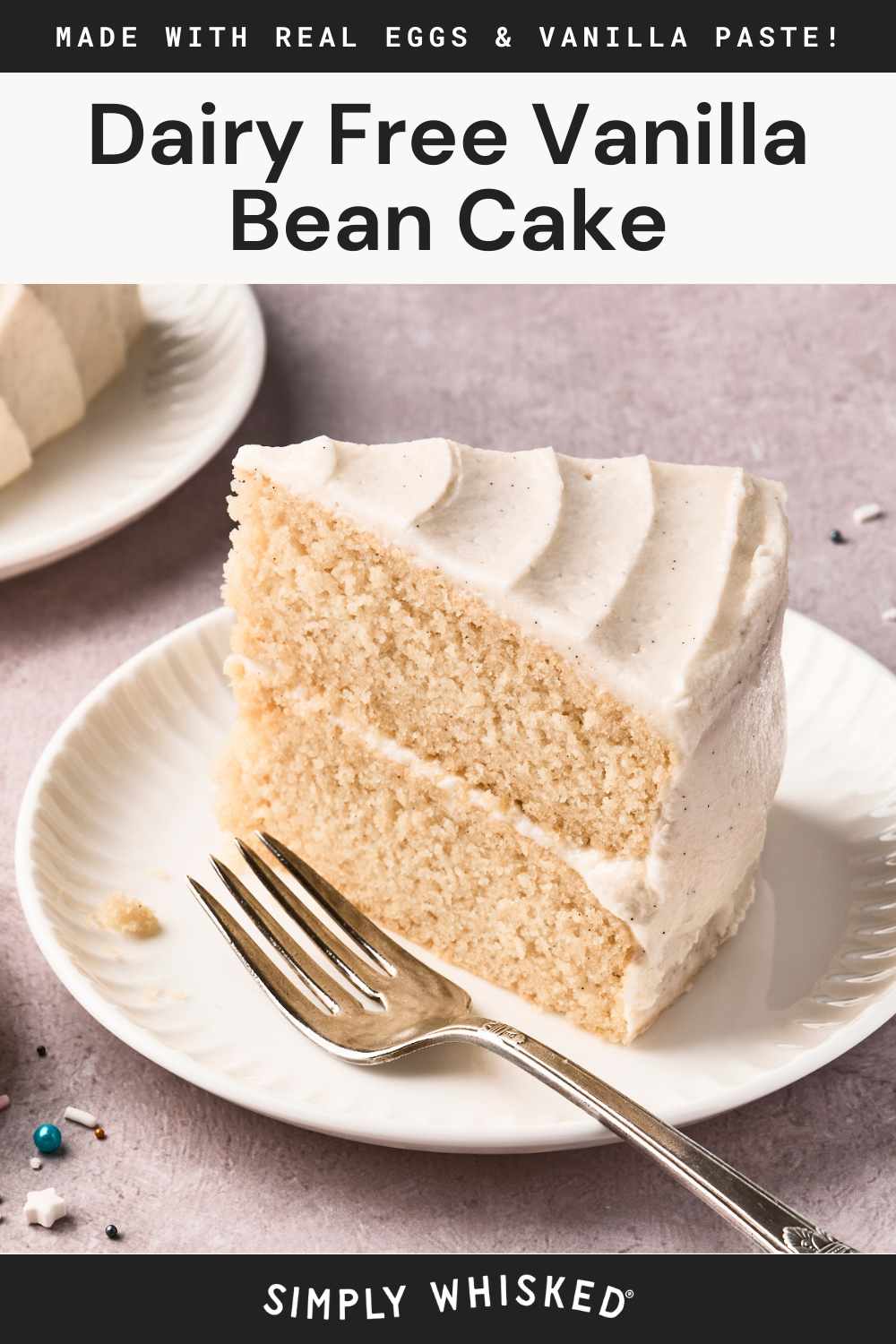 A slice of dairy free vanilla cake with white frosting sits on a white plate beside a fork. The light background and partially visible second slice highlight this delicious treat, with text above and below promoting its dairy-free goodness.