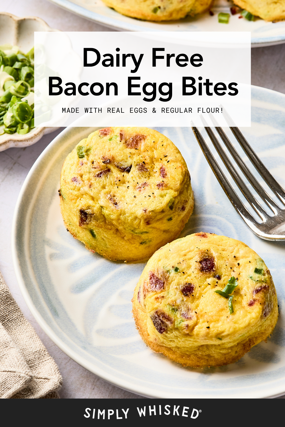 Two dairy-free bacon egg bites are served on a light blue plate with a fork. Chopped green onions are in a small bowl on the side. Text on the image describes the dish as dairy free and made with real eggs and regular flour.
