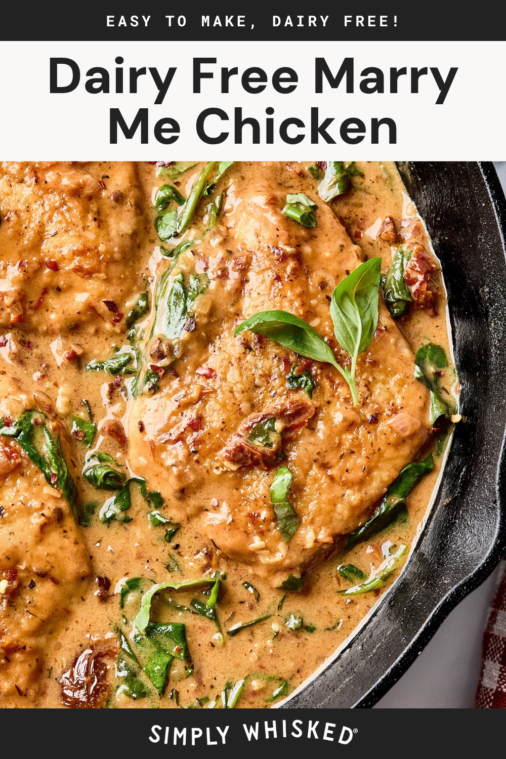 Skillet filled with creamy, dairy-free chicken breasts garnished with fresh basil and spinach in a rich, golden sauce.