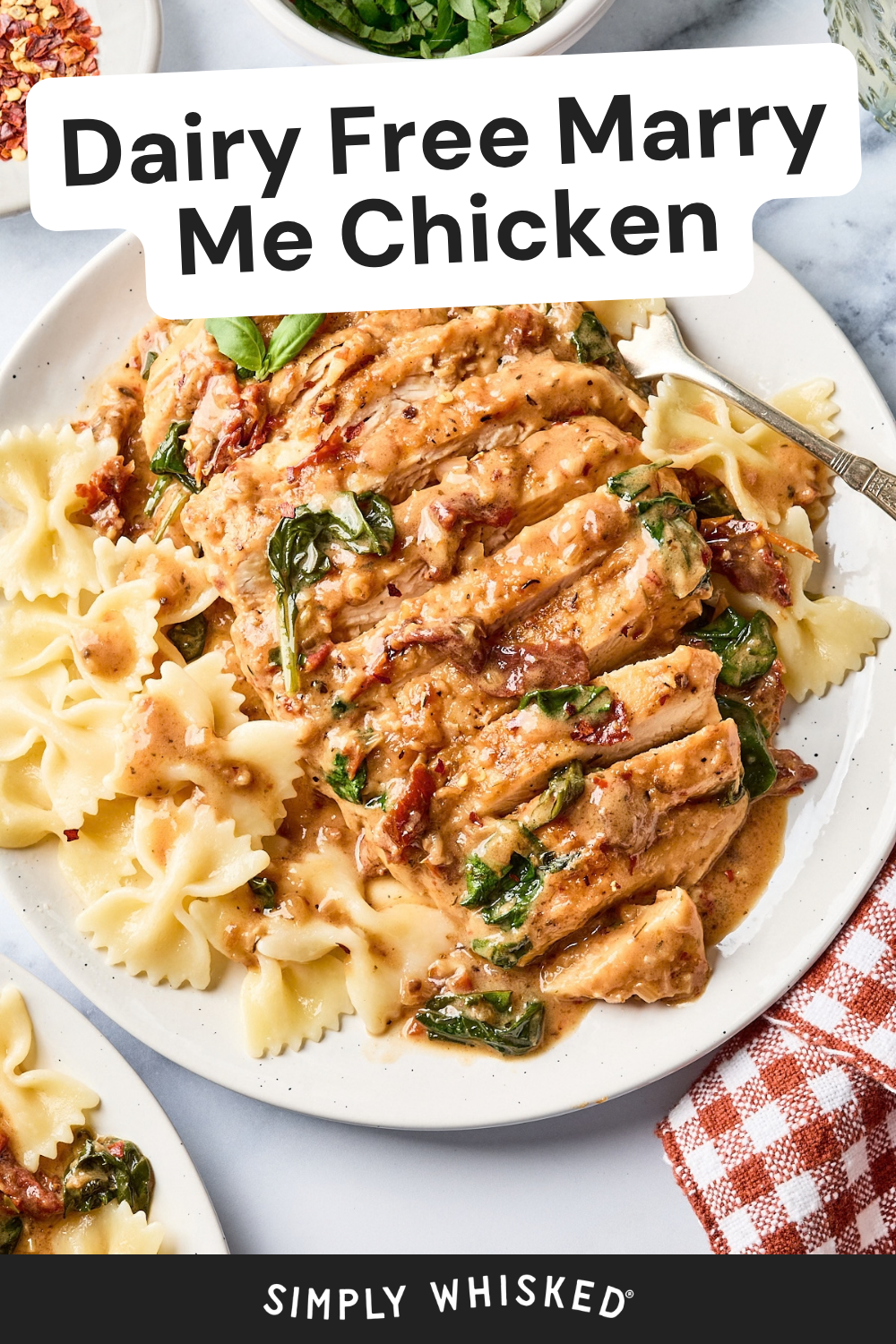 Sliced chicken with creamy sauce, sun-dried tomatoes, and spinach served over bowtie pasta on a white plate, with a checkered napkin beside it. Text reads Dairy Free Marry Me Chicken..