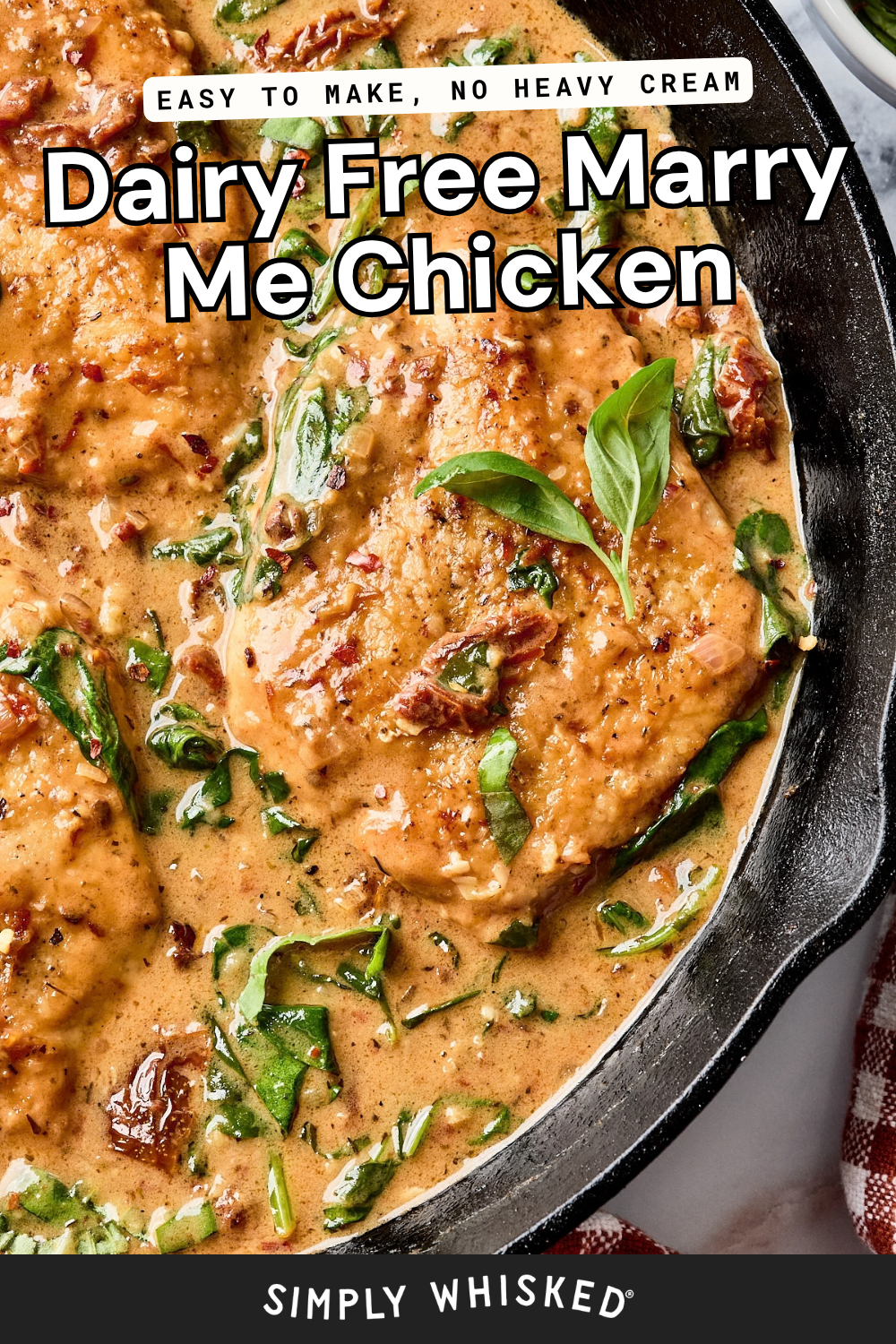 A skillet with creamy dairy-free chicken breasts, sun-dried tomatoes, spinach, and fresh basil. Text reads: Easy to make, no heavy cream. Dairy Free Marry Me Chicken. Simply Whisked..